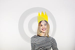 Birthday party, new year carnival. Young smiling woman on white background celebrating brightful event, wears stripped