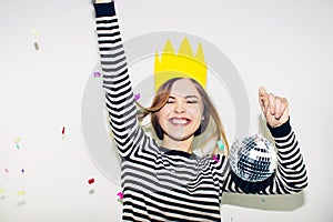 Birthday party, new year carnival. Young smiling woman on white background celebrating brightful event, wears stripped