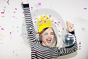 Birthday party, new year carnival. Young smiling woman on white background celebrating brightful event, wears stripped