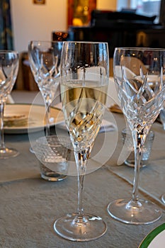 Birthday party, pouring of brut champagne bubbles cava or prosecco wine in tulip glasses with kitchen on background