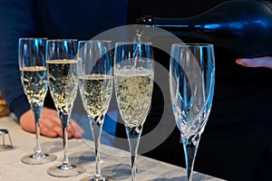 Birthday party, pouring of brut champagne bubbles cava or prosecco wine in tulip glasses with kitchen on background
