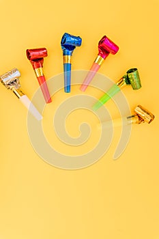 Birthday party whistles on color background.Colorful celebration pattern with party blower horns. Minimal party concept