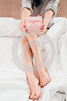Birthday surprise woman legs bed presenting gift