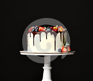 Birthday sweet cake with chocolate drips and fresh fruits Raspberry strawberry blueberry cranberry on dark black