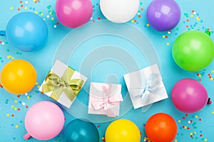 Birthday table with colorful balloons, gift or present box and confetti top view. Flat lay composition.