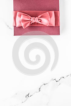 Coral gift box with silk bow on marble background, girl baby shower present and glamour fashion gift for luxury beauty brand,