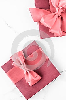 Coral gift box with silk bow on marble background, girl baby shower present and glamour fashion gift for luxury beauty brand,