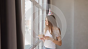 Birthday young woman making wish near window.