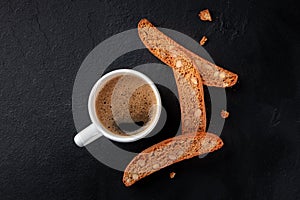 Biscotti. Italian almond cookies with a cup of coffee, shot from the top on a black background
