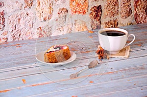 A biscuit cake saucer and a cup of black coffee with cinnamon and anise on a napkin