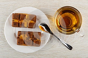 Biscuits with chocolate in plate, spoon, cup with hot tea on wooden table. Top view