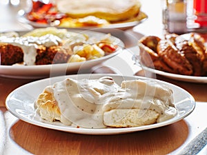 Biscuits and gravy with breakfast foods on plate