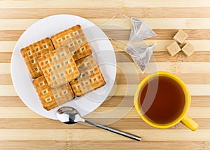 Biscuits sandwiches, cup of tea, lumpy sugar on striped table