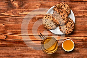 Biscuits with seeds placed near cup of tea and honey