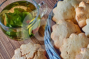 Biscuits in the wicker basket from newspaper tubules and a transparent cup of silverqueen green tea with mint and red currants on