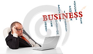 bisinessman sitting at desk and looking laptop with business word cloud