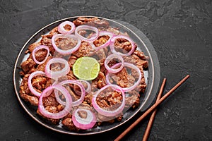 Bistek Tagalog or Bistec Encebollado on black plate on slate table top. Filipino spanish cuisine beef steak with onion photo
