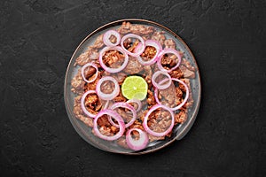 Bistek Tagalog or Bistec Encebollado on black plate on slate table top. Filipino spanish cuisine beef steak with onion photo