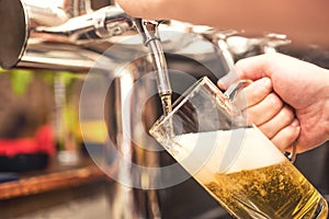 Bistro waiter serving a cold beer. Hand of barman pouring a lager beer from tap