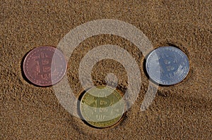 Bit coin gold, silver and bronze coin and printed encrypted money, crypt currency concept in a beach sand