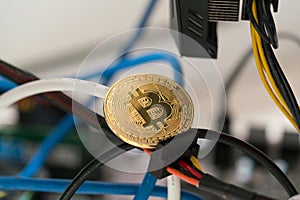 Bitcoin against the background of cables in the rack for crypto-currency mining