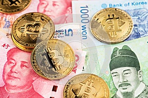 Bitcoin BTC Cryptocurrency coins on China Yuan Renminbi and South Korea Won currency banknotes.