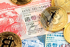 Bitcoin BTC cryptocurrency coins and Hong Kong Dollar HKD currency banknotes.