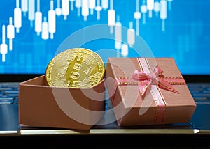 Bitcoin BTC cryptocurrency in a gift box with a stock trading background, gold coin as a symbol of electronic virtual money