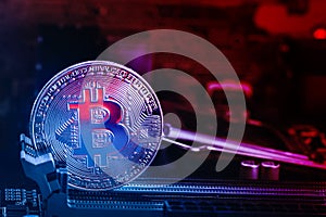 Bitcoin coin with abstract red glow on the background of the motherboard and red blue lights. Symbol of crypto currency - electron