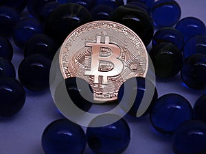 Bitcoin coin between blue glass marbles