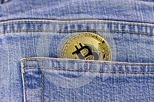 Bitcoin coin in a blue jeans pocket.