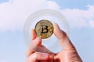 Bitcoin coin in hand on sky background.Business finance investment. Digital technology concept. Business success concept