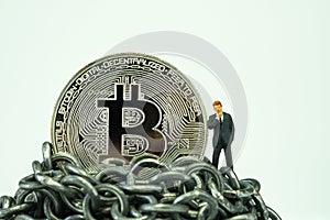 Bitcoin coin and miniature businessman thinking about future price on top of metal chains using as cryptocurrency high price