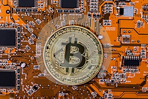 bitcoin coin on orange computer circuit board