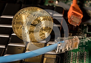 Bitcoin coin standing on keyboard of computer