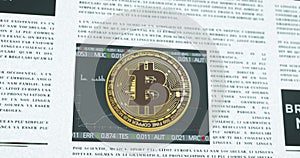 Bitcoin coin symbol in front of financial newspaper with stock market developmen