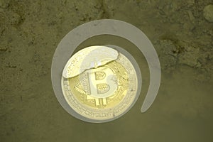 bitcoin coin under water in a puddle crypto currency background concept.