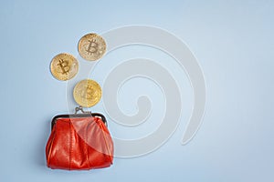 Bitcoin coins falling in red money purse on blue background. Co