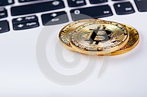 Bitcoin coins on a keyboard of white laptop. Computer. Investment situation. New virtual currency. Most valuable cryptocurrency