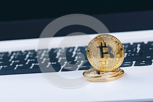 Bitcoin coins on a keyboard of white laptop. Computer. Investment situation. New virtual currency. Most valuable cryptocurrency