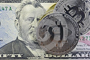 Bitcoin coins lie on a fifty dollar bill