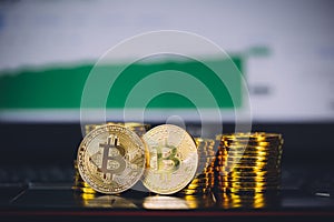 Bitcoin coins pile and two bit coins sitting in front with market spiking and turning green graph chart digital background