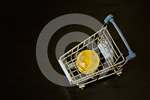 Bitcoin coins in shopping cart. Black background