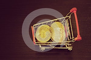 Bitcoin coins in shopping cart. Black background. Top view