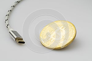 Bitcoin cryptocurrency coin and USB cable on white