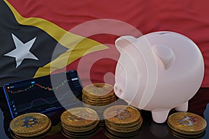 Bitcoin and cryptocurrency investing. East Timor flag in background. Piggy bank, the of saving concept. Mobile application for