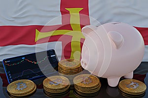 Bitcoin and cryptocurrency investing. Guernsey flag in background. Piggy bank, the of saving concept. Mobile application for