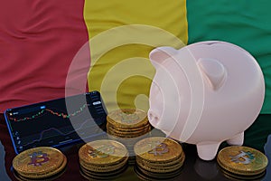 Bitcoin and cryptocurrency investing. Guinea flag in background. Piggy bank, the of saving concept. Mobile application for trading