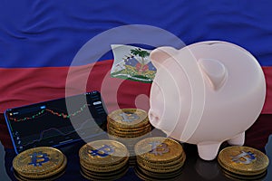 Bitcoin and cryptocurrency investing. Haiti flag in background. Piggy bank, the of saving concept. Mobile application for trading