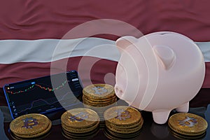 Bitcoin and cryptocurrency investing. Latvia flag in background. Piggy bank, the of saving concept. Mobile application for trading